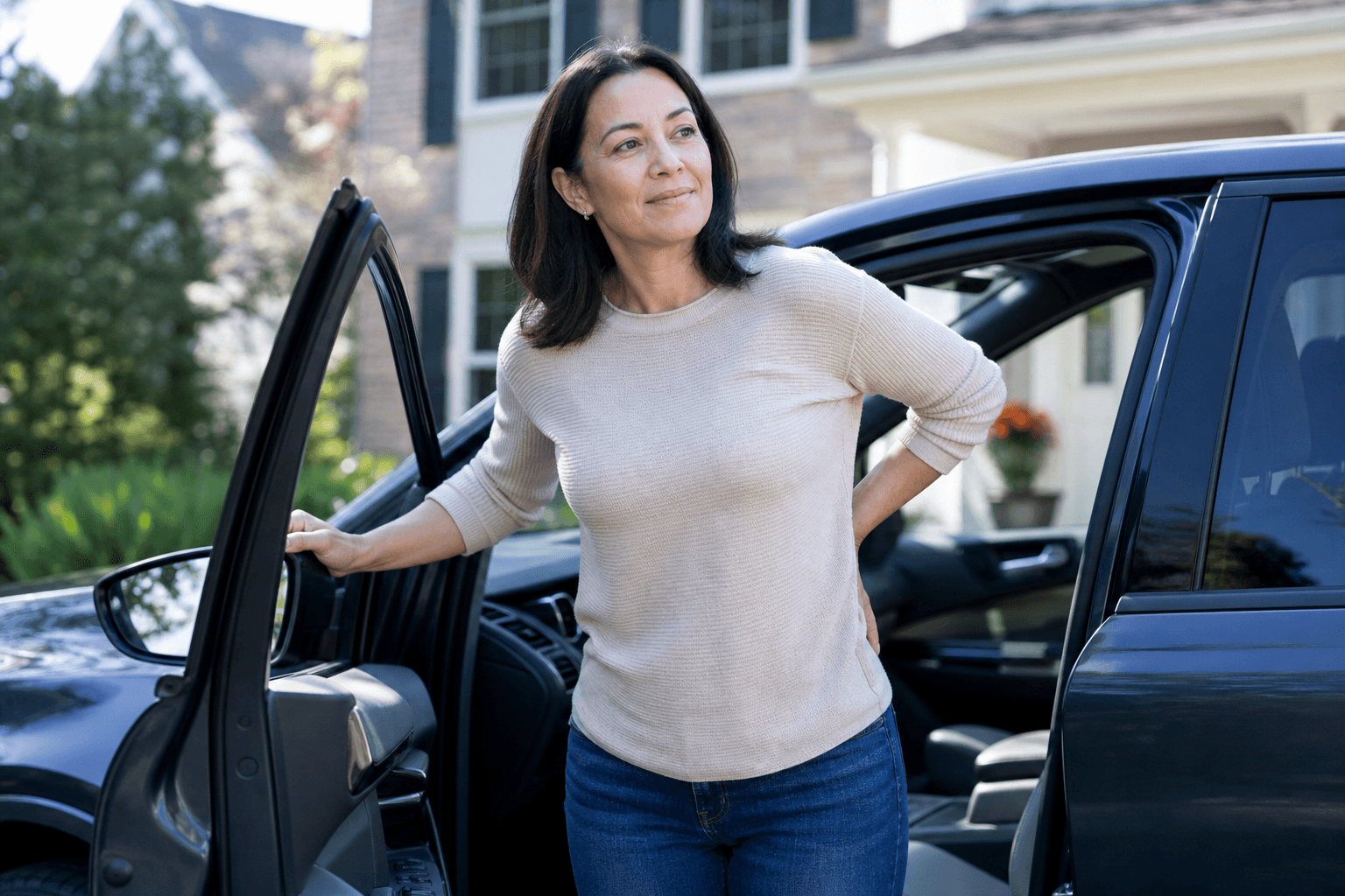 Adult standing after sitting, hand at the low back, looking for back pain relief
